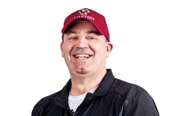 Coach Bill O'Brien laughing and holding a football.